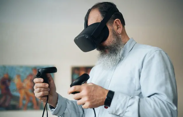 Пожилой человек с бородой тестирует очки виртуальной реальности